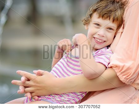 Close-up Portrait Of Beautiful Disabled Girl In The Arms Of His Mother Having Fun In Fountain Of Pub