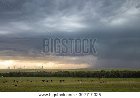 A Supercell Thunderstorm Generates Winds That Blow Dust On The Plains By A Distant Wind Farm.