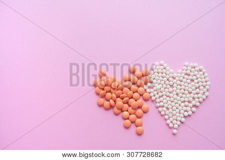 Two Hearts Made Of Homeopathic Globules And Orange Pills On Pink Background. Homeopathy Medicine, He