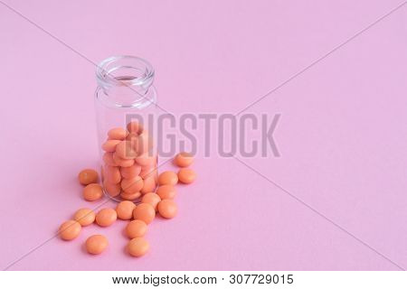 Orange Tablets From Glass Bottle On Pink Background. Copyspace For Text. Epidemic, Painkillers, Heal
