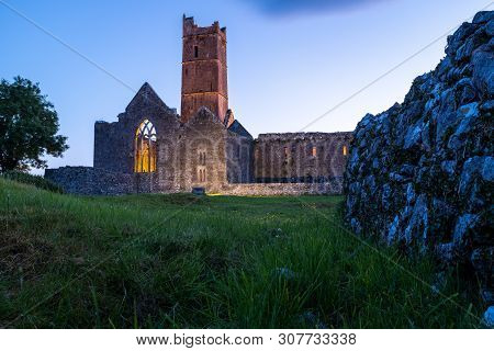 A Low Angle View Of The Ruins Of The Medieval Quinn Abbey In Quinn, Ireland Against A Deep Blue Suns