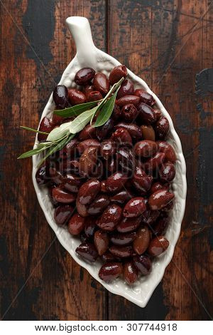 Pitted Kalamata Olives In Bowl On Rustic Wooden Background
