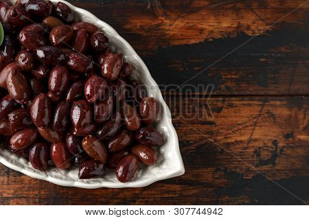 Pitted Kalamata Olives In Bowl On Rustic Wooden Background