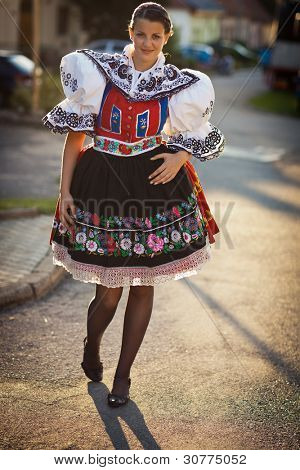 Hagyomány életben tartása: fiatal nő egy gazdagon díszített ünnepi ruha/regionális népviseletben (K