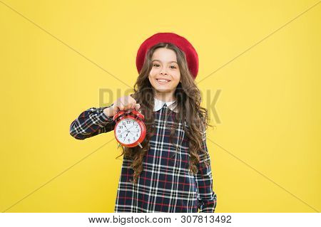 Putting Her Alarm Clock On. Happy Little Girl Holding Alarm Clock On Yellow Background. Small Child 