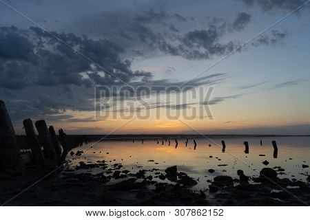 Sunset On The Kuyalnik Liman. Odessa. Ukraine. Old Logs Are Visible From The Water - The Remains Of 