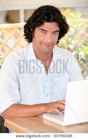 Ritratto di uomo dai capelli scuri bello lavorare sul portatile