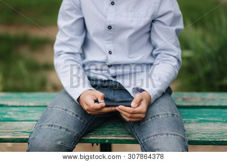 Young Boy Sitting On The Bench And Play Online Games During School Break
