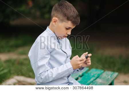 Young Boy Sitting On The Bench And Play Online Games During School Break