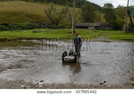 Altai Region, Russia - September 4, 2018: Local Residents Wade Through A Mountain River Yarivka In T