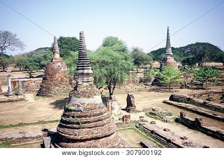 Buddhist Stupas Stand Among The Ancient Ruins Of Wat Phra Mahathat In Ayutthaya, Thailand.