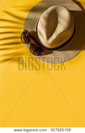 Hat And Glasses On Bright Yellow Background With Tropical Leaf Shadow, Creative Pastel, Beach Concep
