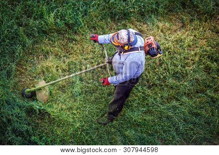 Top View Fat Dirty Lawnmover Man Worker Cutting Dry Grass With Lawn Mower.