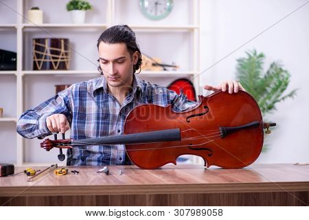 Young handsome repairman repairing violin