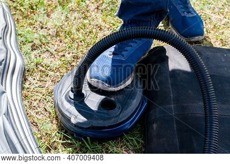 A Fisherman Pumps An Inflatable Boat With A Foot Pump. Inflatable Boat Pumping Process, Close-up.