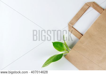 Ecology. Eco-friendly Paper Bag-kraft And Green Leaf On White Background. The Concept Of Zero Waste.