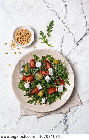 Healthy Vegetarian Salad With Fresh Arugula, Cherry Tomatoes, Soft Cheese, Olives And Pine Nuts