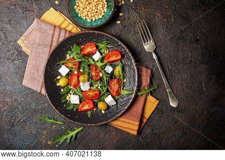 Healthy Vegetarian Salad With Fresh Arugula, Cherry Tomatoes, Soft Cheese, Olives And Pine Nuts