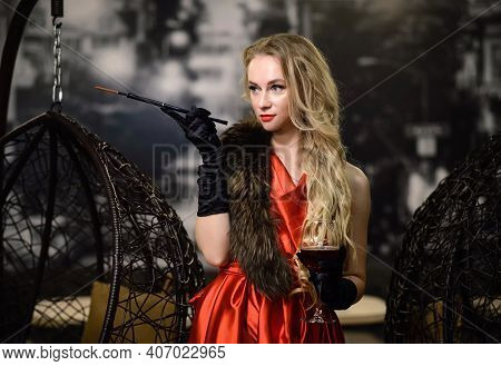 A Woman In A Red Dress With A Cigarette Holder And A Glass Of Wine. Smoking Lady. Old Fashioned Make