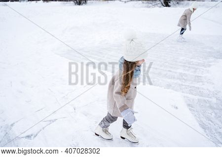 Beautiful Little Cute Girl Learn To Skate On Ice Skating Rink In Park. Fall Down And Have Fun. Styli