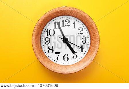 A Wooden Round Clock On Yellow Background.