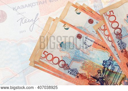 5000 Kazakhstani Tenge Bills Lies In Stack On Background Of Big Semi-transparent Banknote. Abstract 