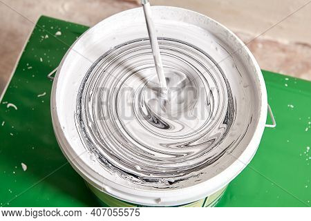 House Painter Mixes Black And White Paint To Get A Gray Color Using An Electric Drill And Paddle Mix