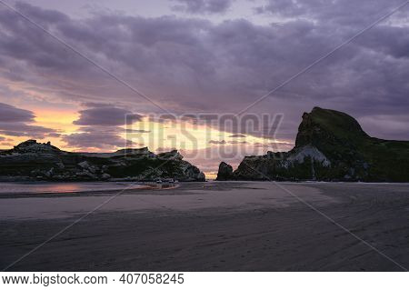 Dramatic Sunset At The Beach With Big Rock Formations. Castle Rock, New Zealand.