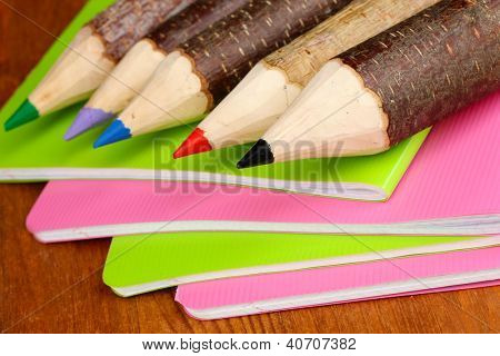 Kolorowe kredki drewniane z exercisebooks na drewnianym stole