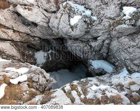 Doline Or Sinkhole With Snow Patches In Alpine Landscape In Winter