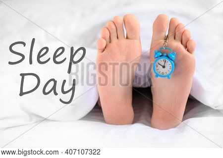 . Sleep Day. A Man Lies In Bed, An Alarm Clock Hangs On His Leg, The Concept Of Laziness, World Slee