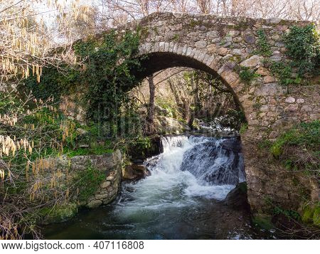 Mountain Stream Rushing Through A Woodland And Cascading Beneath An Ancient Genoese Bridge Near Feli