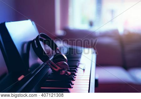 Soft Focus Digital Piano Keyboard With Modern Headphones For Music With Blurry Of Sofa Background, C