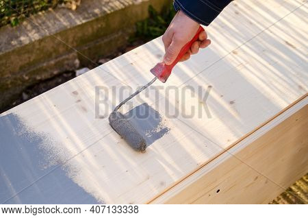 Close Up Of Painter Arm Painting A Wall With Paint Roller, Wood Wardrope Is Painted By Grey Color Pa