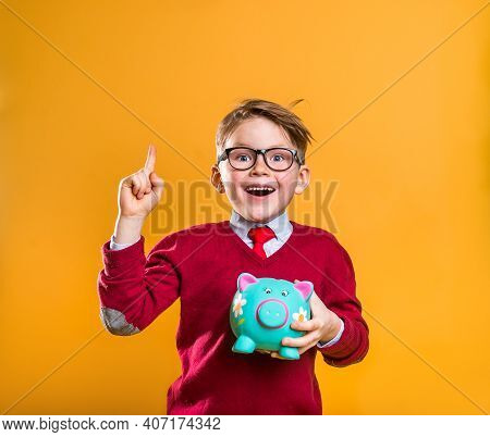 Happy School Boy With Money Pointing Up Isolated On Yellow. Cool Stylish Businessman. How To Be Rich