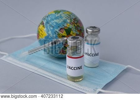 Close Up Image Of Two Ampoules With Vaccine And Inscription On Them, Syringe And Little Toy Globe On