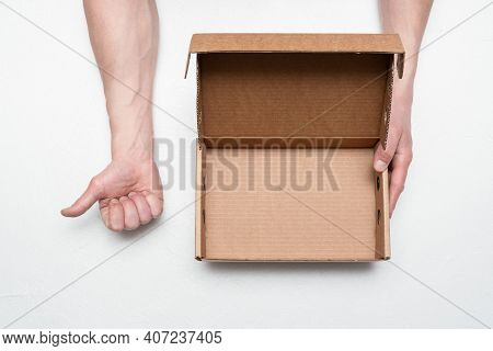 Empty Cardboard Box With Copy Space In The Male Hand And Thumbs Up Gesture By The Hand On The Gray B
