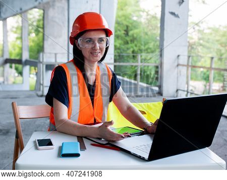 Construction Management. Woman Manager At A Construction Site. Woman In A Robot Builder Vest With A 