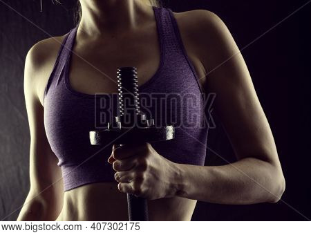Slim Athletic Woman Holding Dumbbell In The Hand On Black