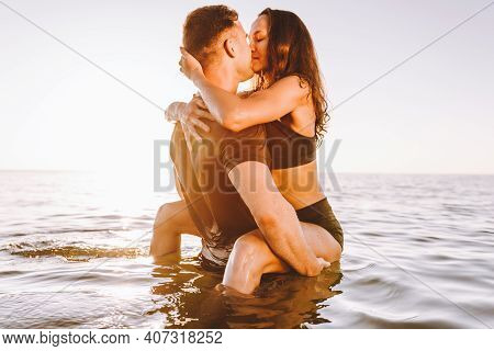 Happy Young Fit Couple In The Sea Or Ocean Hug Each Other With Love At Summer Sunset. Online Dating,