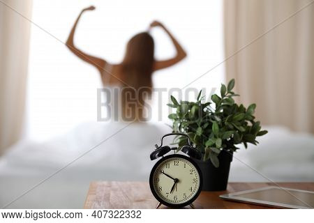 Alarm Clock Standing On Bedside Table Has Already Rung Early Morning To Wake Up Woman Is Stretching 
