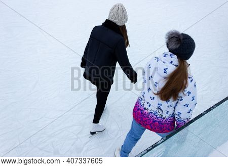 Close-up Of Girls Ice Skating In Winter On An Outdoor Ice Rink. Ice Skates Of Two Friends Ice Skatin