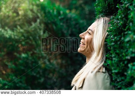 Side Portrait Of Blonde Smiling Woman Breathe With Fresh Air In Green Forestor Park In Summer Wearin