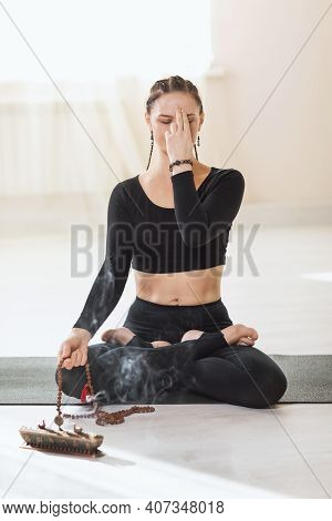 A Woman In Black Sportswear Practicing Yoga Sitting On A Gymnastic Mat In A Lotus Position Is Engage