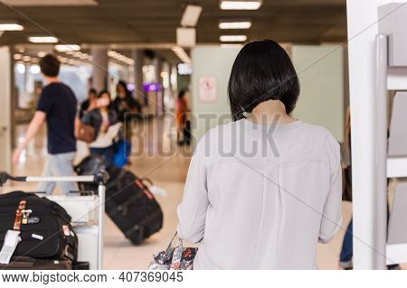 Woman Toruist At The Airport With Tluggage Waiting For Departure.