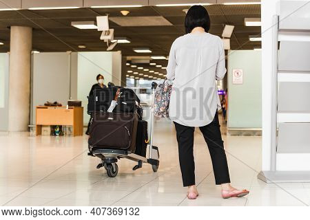 Woman Toruist At The Airport With Trolley Bag Waiting For Departure.