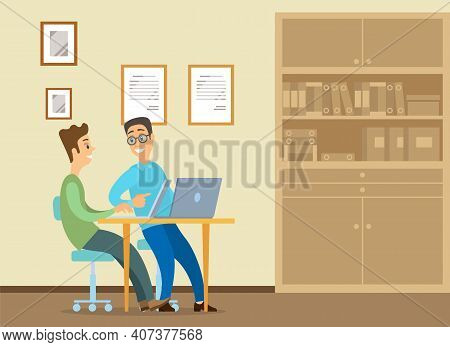 Young Man Is Sitting At A Desk With Laptop, His Colleague Is Pointing To A Screen And Giving Advice.