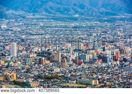 Kofu, Yamanashi, Japan downtown city skyline from the mountains at dusk.