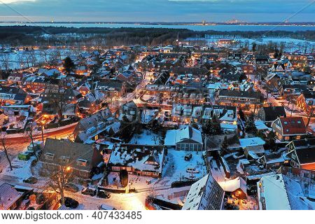 Aerial from a snowy village Huizen in winter in the Netherlands at twilight
