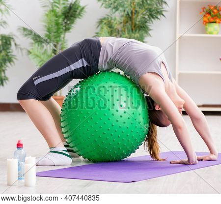 Young woman exercising with stability ball in gym